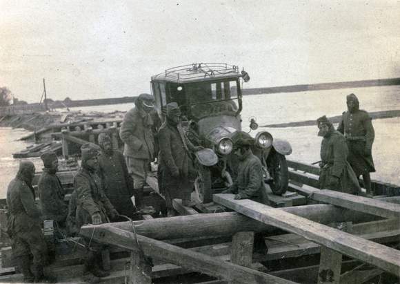 Many hands were needed to get this JDC vehicle across a river on a crude wooden bridge during a field trip to Rovno, Dubno, and Polonnoye. By November 1920, the Poland Branch had 20 cars and 40 trucks for such trips. Poland (now Ukraine), c. 1920, <em>NY_01703</em>. 
