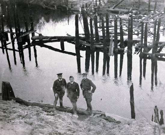 The destruction of a bridge between Brest and Kobryn was one of numerous obstacles that JDC field representatives faced. Abraham Zucker and I. M. Kowalsky posed en route with a Polish Government representative. Poland (now Belarus), c. 1920. <em>NY_01731</em>.