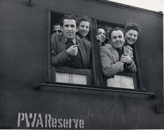 Jewish refugees from the DP camps of Germany peer out from the windows as their train arrives in the local railroad station. Marseille, France, c. 1949. Photographer: Al Taylor.